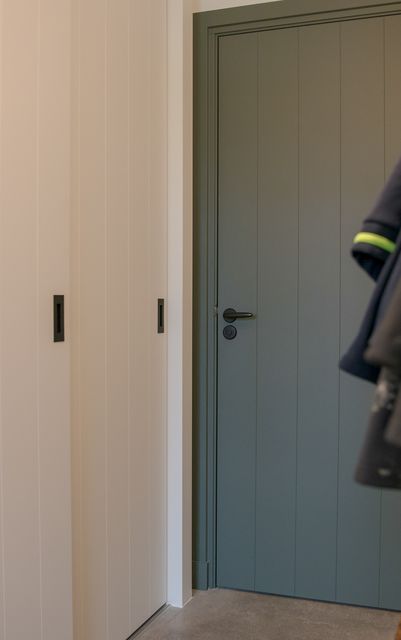 Close-up van de rand en het beslag van een grijsgroene deur.