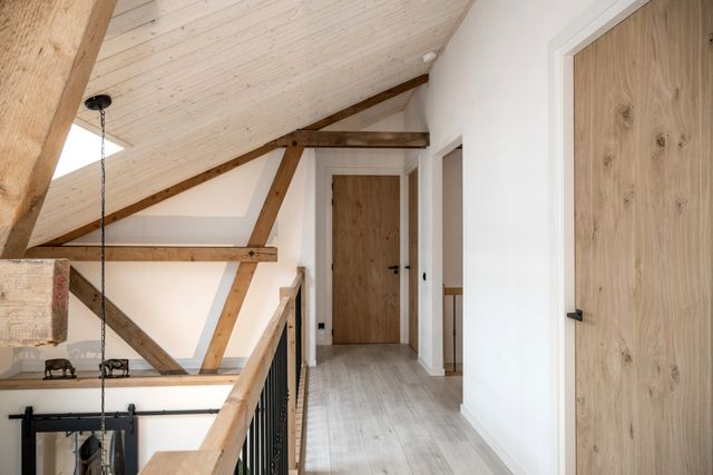 Houten deur en zichtbare houten dakconstructie op een overloop.