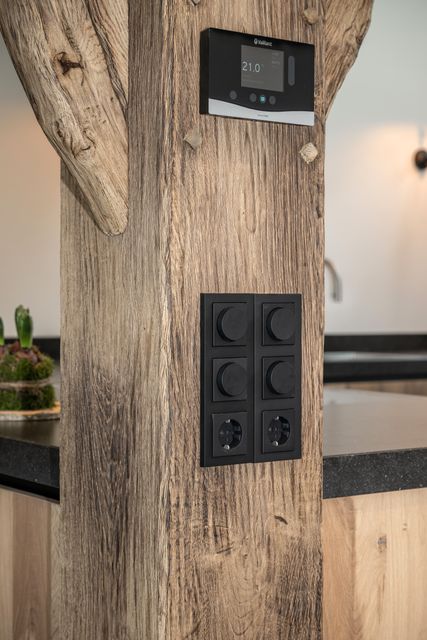 Donkere schakelaars en een bedieningspaneel op een houten staander.