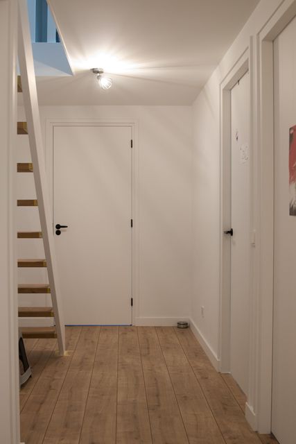 Witte deuren langs een gang met een houten vloer.