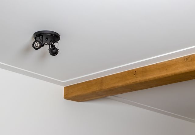 Houten balk met een verticale aansluiting tegen een witte wand en plafond.