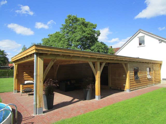 Houten buitengebouw met een open overkapping en een betegeld terras.